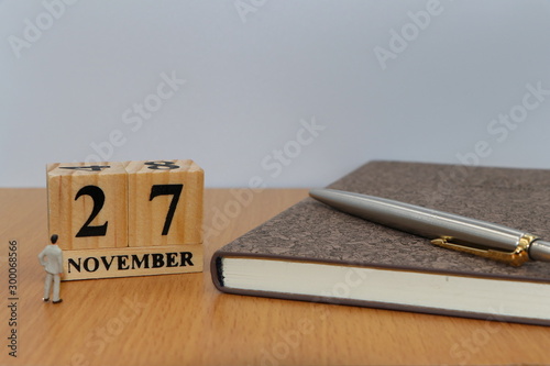 November  27, a calendar photo from the wood The table top consists of a book and pen that is ready to use. White background
