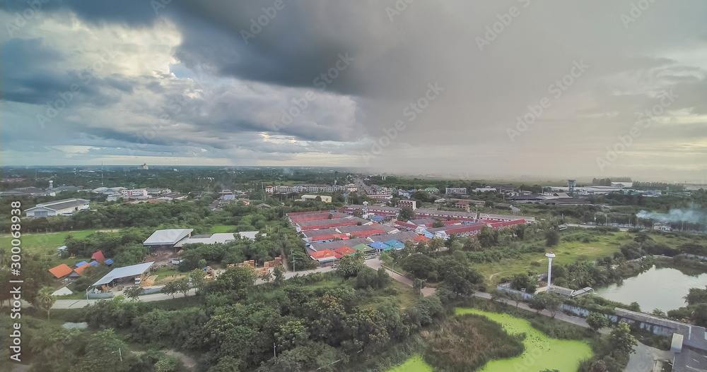 Aerial view evening above village and green rice paddy fields with heavy raining in dark sky background, Krajub reservoir, Ban Pong, Ratchaburi, Thailand.