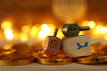 religion concept of of jewish holiday Hanukkah with wooden dreidels (spinning top) and chocolate coins over wooden table and bokeh lights background