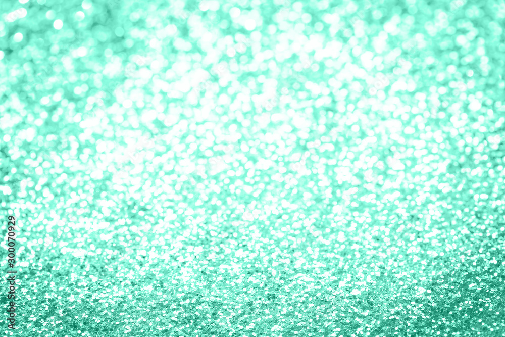 Obraz premium Trendy monochrome bokeh lights background in shades of pastel green color. Festive confetti glitter backdrop