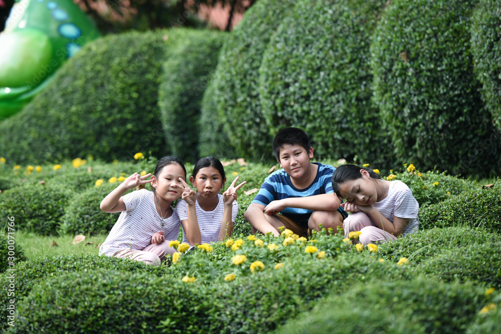 Happy Asian preteen boy and his sisters travel the green park outdoor.