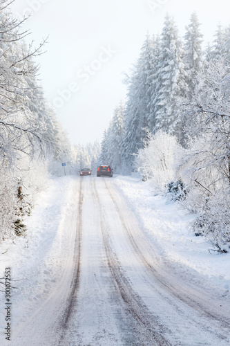 Two cars meeting on a narrow winter road in the forest