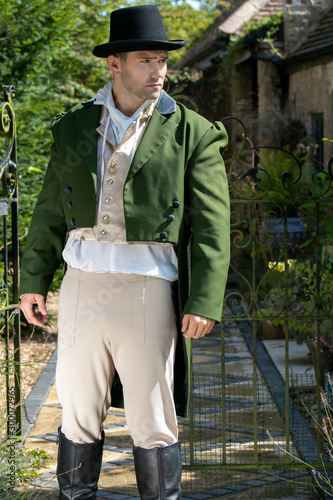Portrait of handsome gentleman dressed in vintage costume and top hat standing in stately home courtyard photo