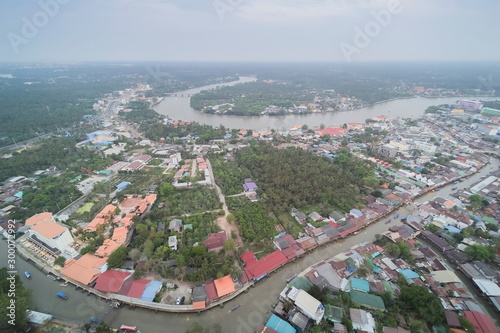 Aerial view above canal, river and city around with many boats and house with cloudy sky background, Amphawa floating market, Samut Songkhram, Thailand.