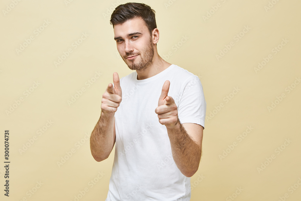 Horizontal shot of handsome charismatic young man with black hair and stubble posing isolated pointing fore fingers at camera, having confident flirty facial expression, choosing you. Body language Horizontal shot of handsome charismatic young man with black hair and stubble posing isolated pointing fore fingers at camera, having confident flirty facial expression, choosing you. Body language