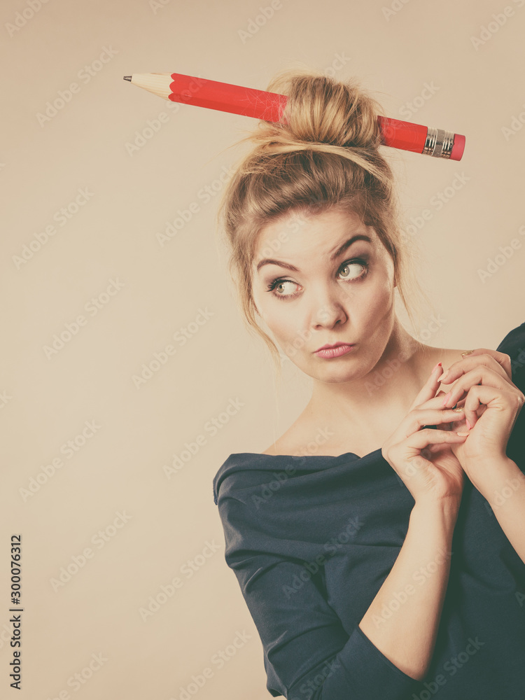 Obraz premium Thinking blonde woman having big pencil in hair