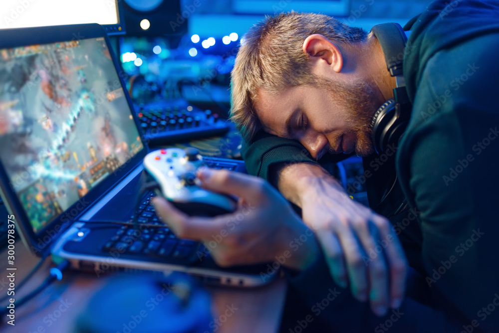 Male gamer sleeping at his laptop after challenge - obrazy, fototapety, plakaty 