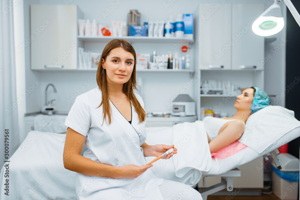 Cosmetician near female patient on treatment table Cosmetician near female patient on treatment table