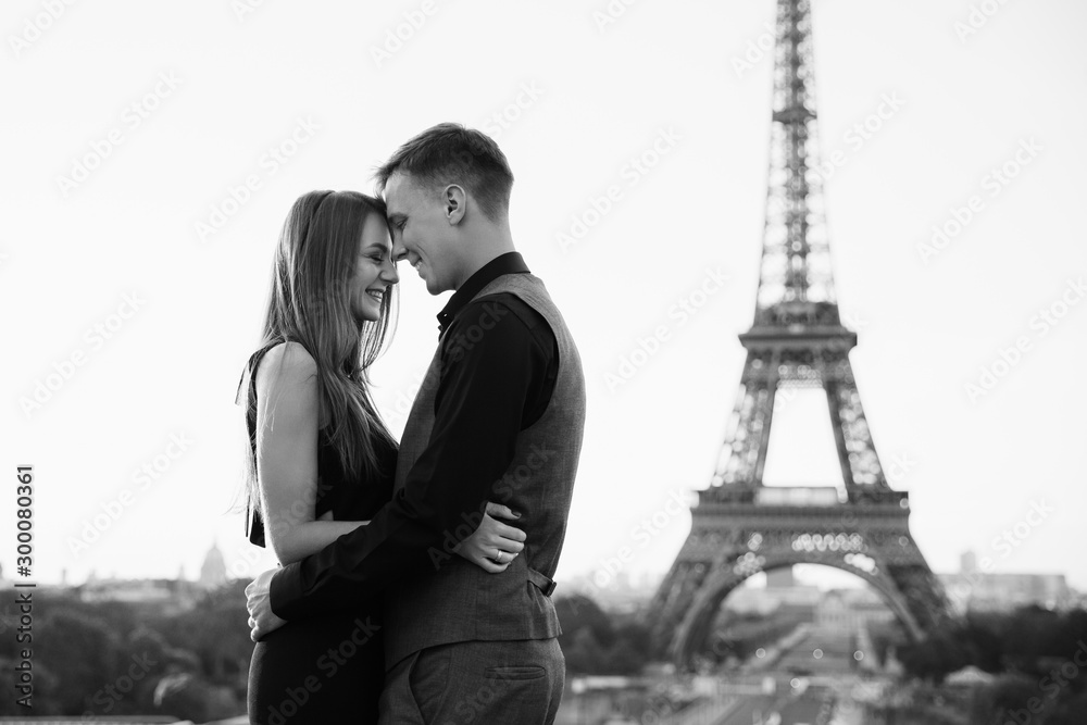 Black and white photo, smiling couple in love near the Eiffel tower. Romantic date, honeymoon in Paris
