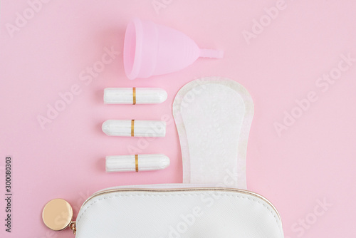 menstrual cup, tampons and menstrual pads in a cosmetic bag on a pink background. woman period concept.
