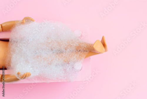 doll man legs in pink bath on pink pastel background. creative minimalistic concept of relax. top view. 