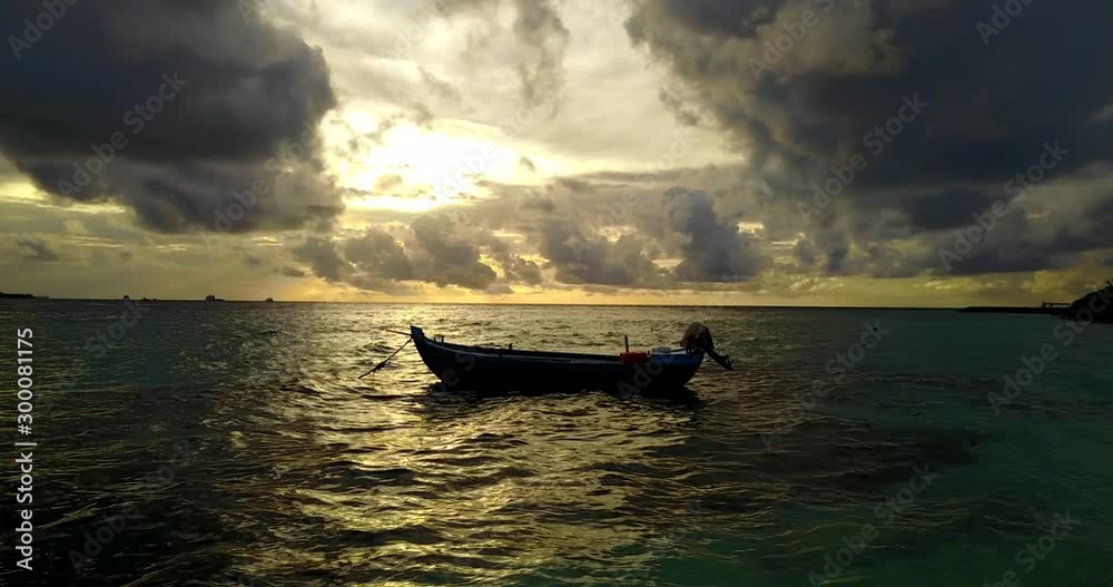 Sun setting on golden horizon behind big stormy dark clouds, fishing boat floating in the shallow water Sun setting on golden horizon behind big stormy dark clouds, fishing boat floating in the shallow water