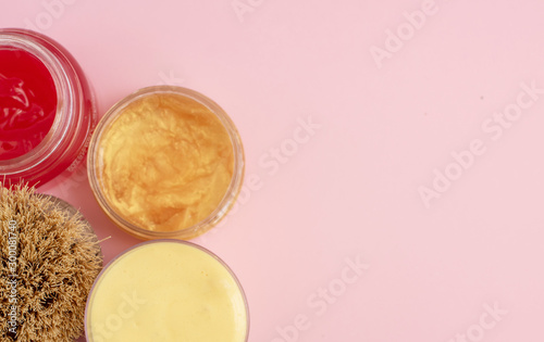 body brush and skin care cream on a pink pastel background
