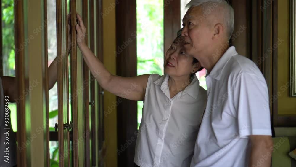 Asian senior elder couple looking at memory objects in cabinet good time Asian senior elder couple looking at memory objects in cabinet good time