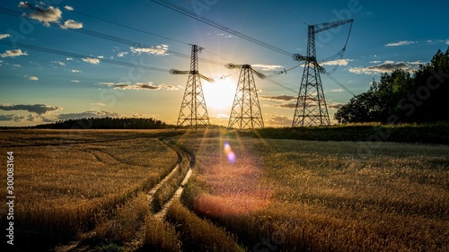 Dirt road leading toward electricity pylons at sunset