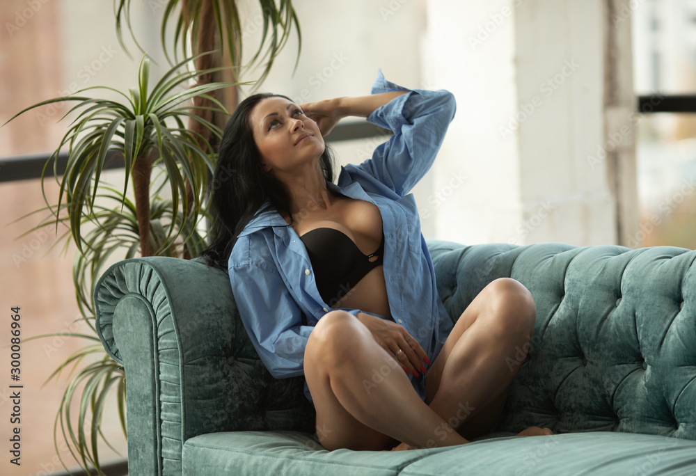 Beautiful sexy woman in black lingerie sitting on coach at home. Beautiful sexy woman in black lingerie sitting on coach at home.
