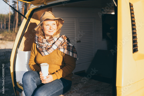 Young blonde Caucasian woman relaxing in her campervan at sunset photo