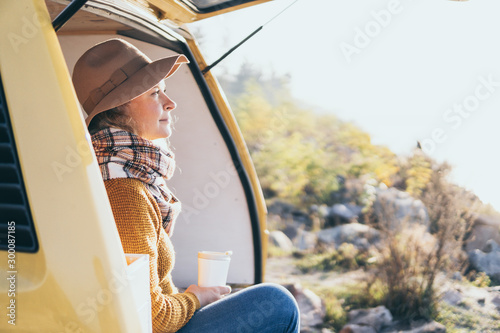 Young blonde Caucasian woman relaxing in her campervan at sunset