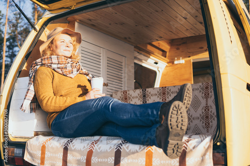 Young blonde Caucasian woman relaxing in her campervan at sunset photo