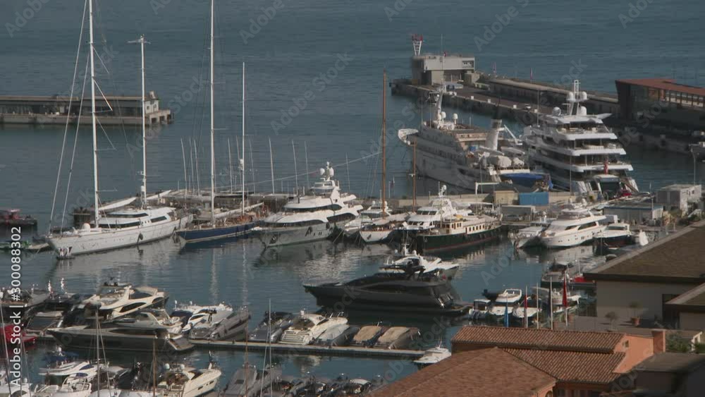 Aerial: Luxury yachts with sailboats moored by jetty at Port Hercules in city on sunny day - Monte Carlo, Monaco
