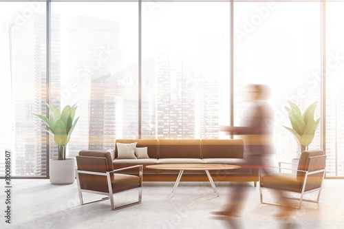 Man walking in panoramic lounge with brown sofa