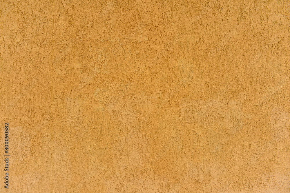 The wall of the building with a speckled surface of clay stucco beige brown. Background The wall of the building with a speckled surface of clay stucco beige brown. Background