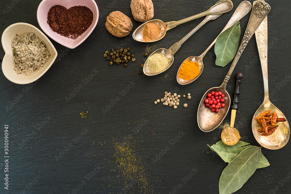 Various of spices in the vintage spoons on the black slate background with copy space