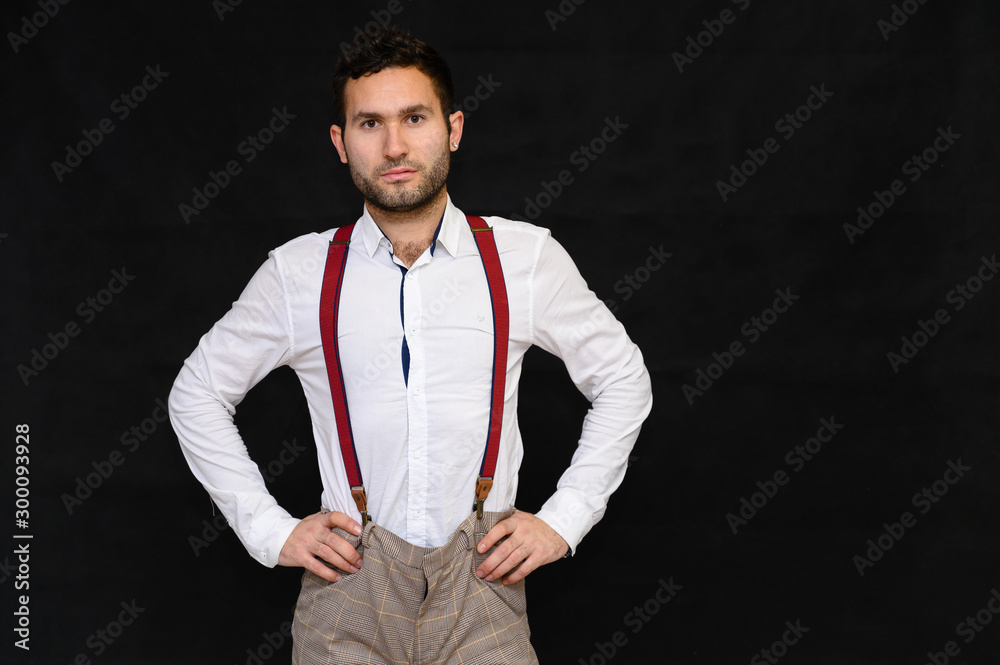 Men's fashion concept. Portrait of a handsome male model with perfect body wearing a white shirt posing on a black background. Black hair. Close Studio Shot