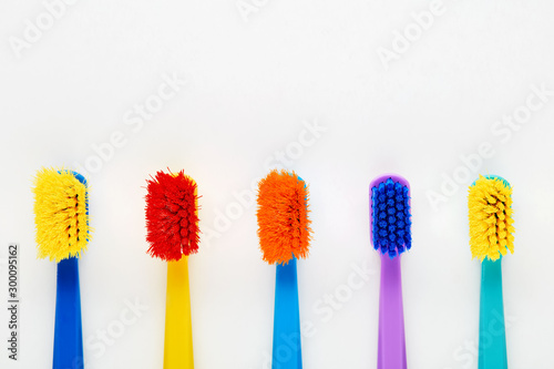 Colorful old worn toothbrushes and a new toothbrush displayed in a row on white background
