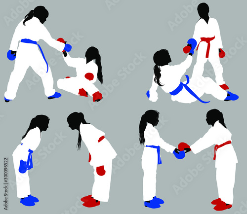 Teenage karate girls in white kimonos and blue and red outfits help each other out in training and show respect before the fight.