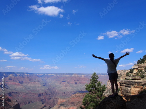 A man with her arms raised is impressed to see the spectacular view of the valley, Grand Canyon National Park, Arizona, USA