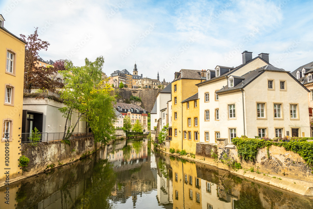 Alzette river bend with houses reflected in water and cathedral on the hill, Luxembourg city, Luxembourg