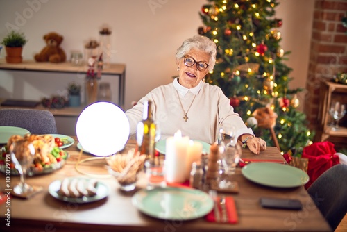 Adorable senior woman smiling happy and confident. Sitting prepared to celebrate christmas at home