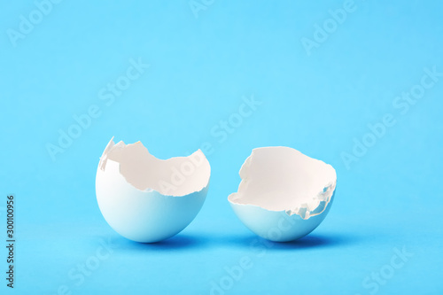 One white broken egg shell on blue background