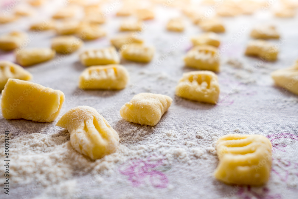 display of fresh traditional  homemade italian gnocchi pasta on table cloth with flour with soft natural light