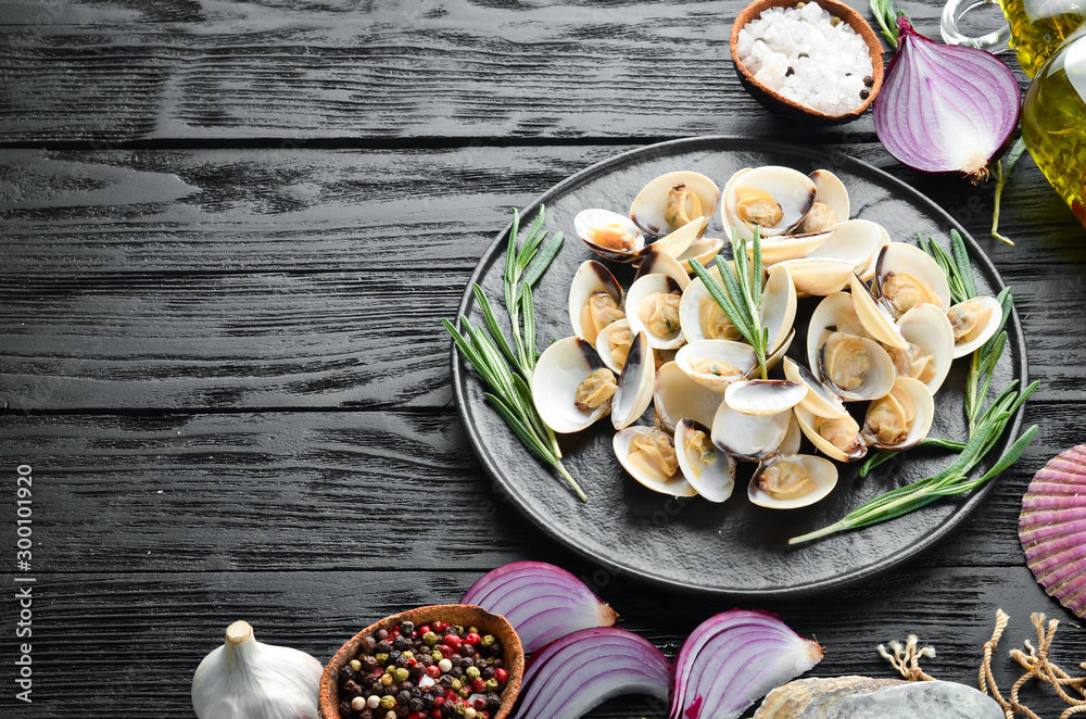 Boiled clams with spices in a plate. Seafood on black background. Top view. Free copy space. Boiled clams with spices in a plate. Seafood on black background. Top view. Free copy space.