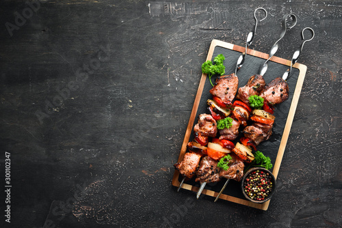 Shish kebab BBQ meat with onions and tomatoes. On a black background. Top view. Free space for your text. Rustic style. photo