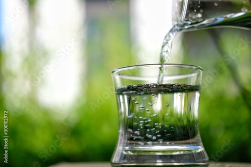 glass of water with ice on green background