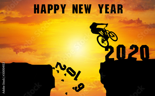 Happy New Year 2020 Silhouette . Men riding mountain biking figures 2019. Then jump over the cliff to come to 2020  at Sunset time