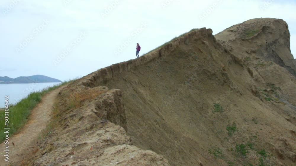 Girl traveler coming to the edge of the cliff in the mountains Girl traveler coming to the edge of the cliff in the mountains