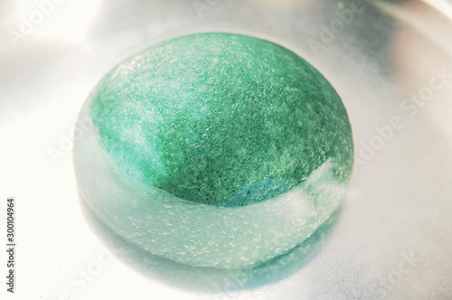 Light green konjac sponge in water. Facial massage and exfoliating beauty accessory.