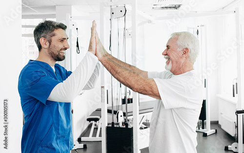 Senior man and Physical Therapist have five after successful physio treatment. physio rehabilitation