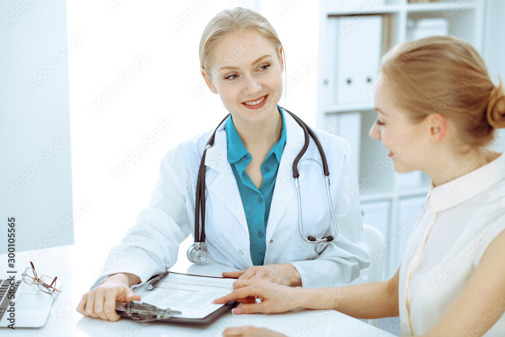 Doctor and patient talking in hospital office while sitting at the desk. Health care and client service in medicine Doctor and patient talking in hospital office while sitting at the desk. Health care and client service in medicine