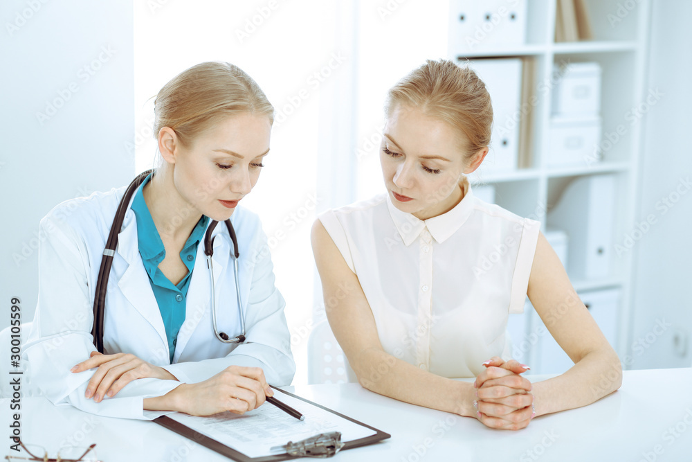 Doctor and patient talking in hospital office while sitting at the desk. Health care and client service in medicine Doctor and patient talking in hospital office while sitting at the desk. Health care and client service in medicine