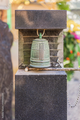 Small bronze bell hanging at the foot of Habataki Kanzeon Bosatsu statue in Tabata Togakuji temple in Tokyo. photo