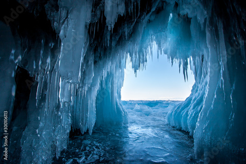 View from the ice cave on Lake Baikal. Many beautiful icicles on the walls and ceiling. Thick and thin icicles. Ice on the floor. photo
