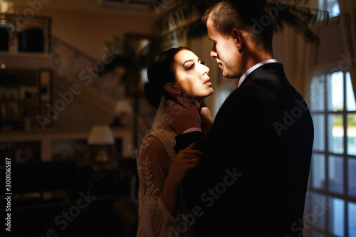 Young married couple in darkness. Newlyweds enjoy each other tenderly. Intimate atmosphere. Luxury elegant wedding couple kissing and embracing. Romantic moment. Together. Wedding.