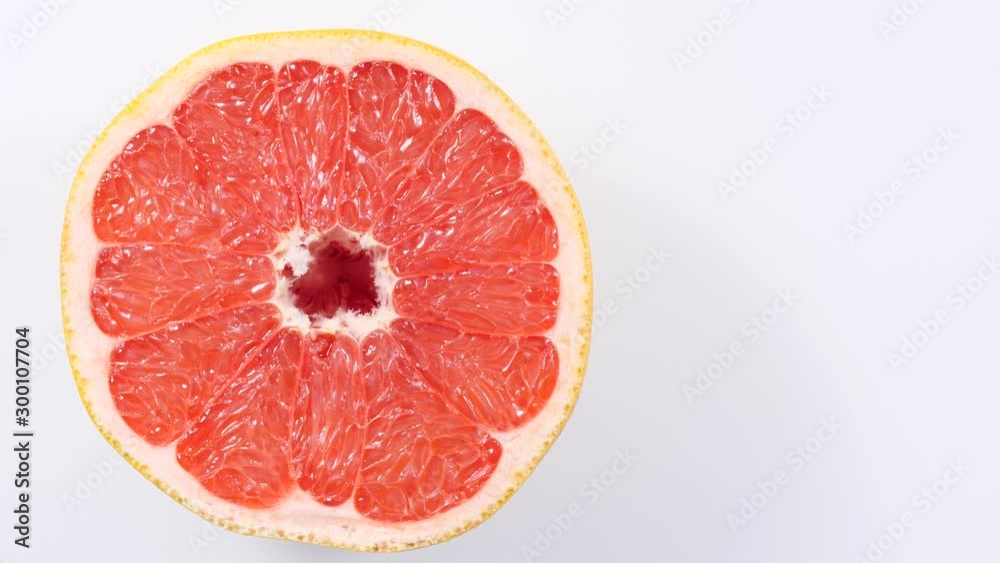 Fresh half of grapefruit citrus fruit on plate rotating. Healthy eating, weight loss, light meal. Top view Fresh half of grapefruit citrus fruit on plate rotating. Healthy eating, weight loss, light meal. Top view