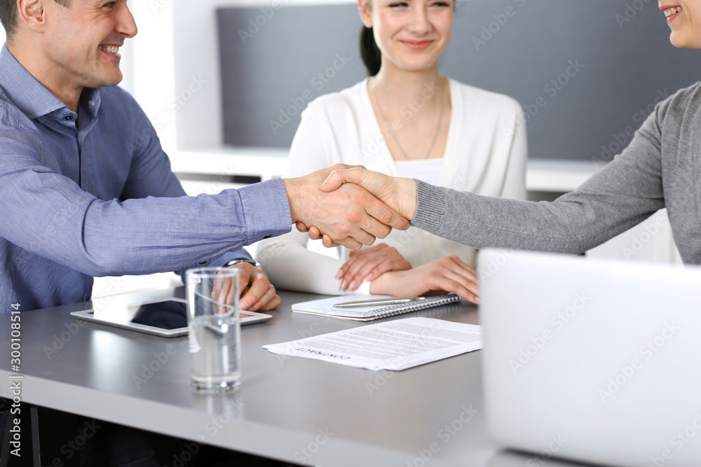 Fototapeta premium Group of business people shaking hands after discussing questions at meeting in modern office. Handshake close-up. Teamwork, partnership and agreement in business concept