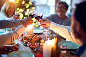 Family and friends dining at home celebrating christmas eve with traditional food and decoration, all sitting on the table together